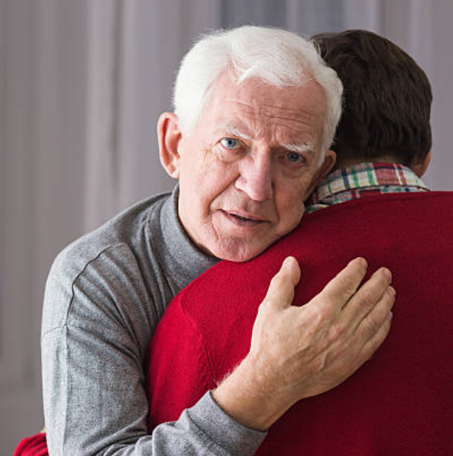 photo of older man hugging younger person